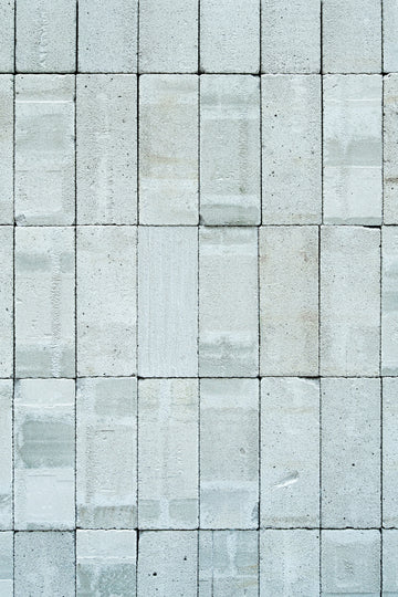 A wall constructed from rectangular grey concrete blocks with a textured surface
